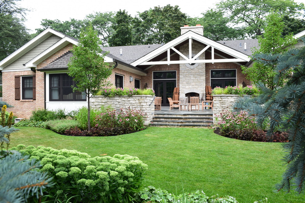 This is an example of a mid-sized traditional backyard partial sun garden for summer in Chicago with natural stone pavers and a retaining wall.