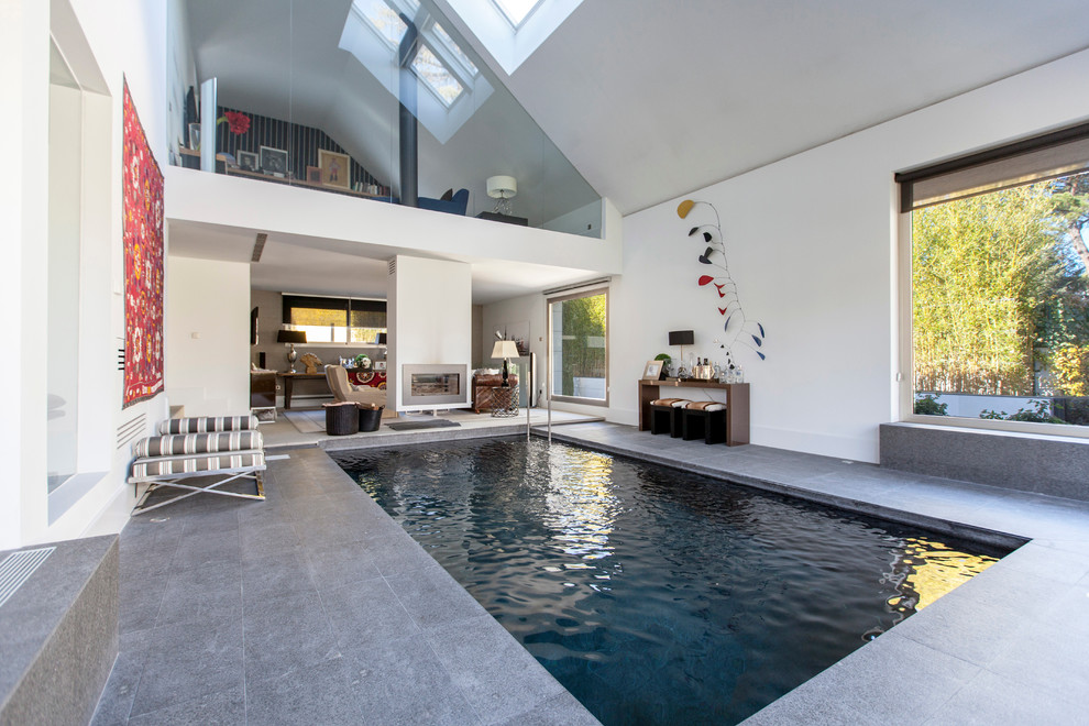 Photo of an expansive contemporary indoor rectangular pool in Madrid with a pool house.
