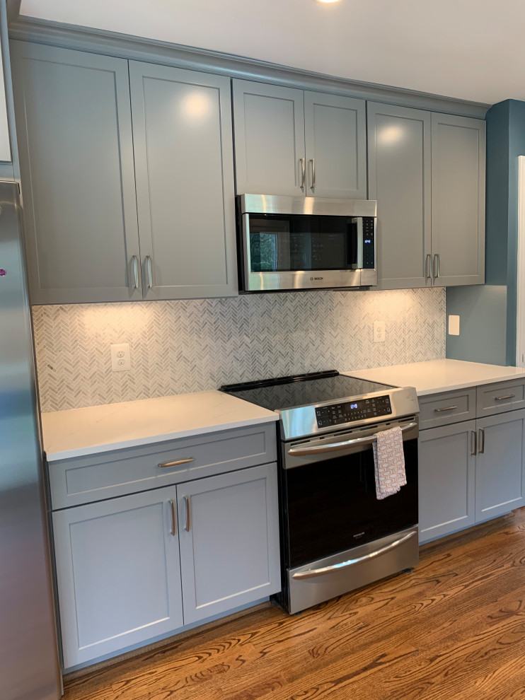 Inspiration for a mid-sized traditional u-shaped separate kitchen in DC Metro with a single-bowl sink, shaker cabinets, grey cabinets, quartzite benchtops, grey splashback, ceramic splashback, stainless steel appliances, medium hardwood floors, with island, brown floor and white benchtop.