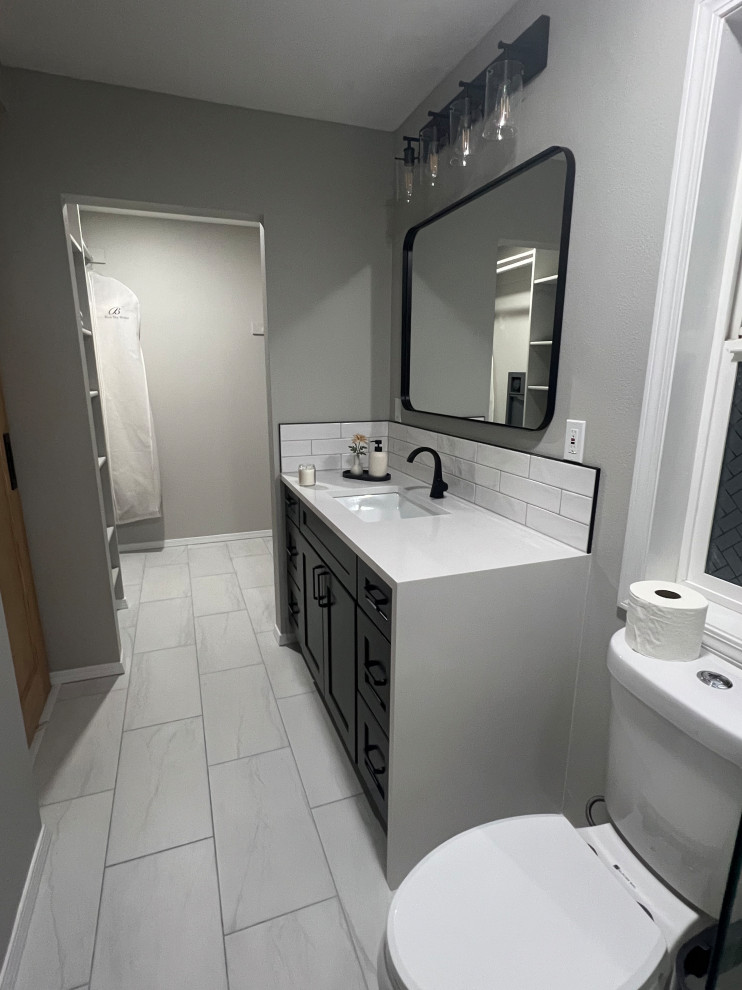 Cette image montre une douche en alcôve principale minimaliste de taille moyenne avec un placard à porte shaker, des portes de placard noires, WC séparés, un carrelage blanc, des carreaux de céramique, un mur gris, un sol en carrelage de porcelaine, un lavabo encastré, un plan de toilette en quartz, un sol blanc, une cabine de douche à porte coulissante, un plan de toilette blanc, des toilettes cachées, meuble simple vasque, meuble-lavabo sur pied et un plafond à caissons.
