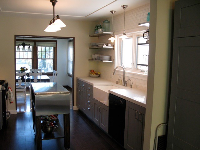 Mid-sized transitional galley dark wood floor enclosed kitchen photo in Seattle with a farmhouse sink, shaker cabinets, blue cabinets, quartz countertops, white backsplash, ceramic backsplash, black appliances and an island