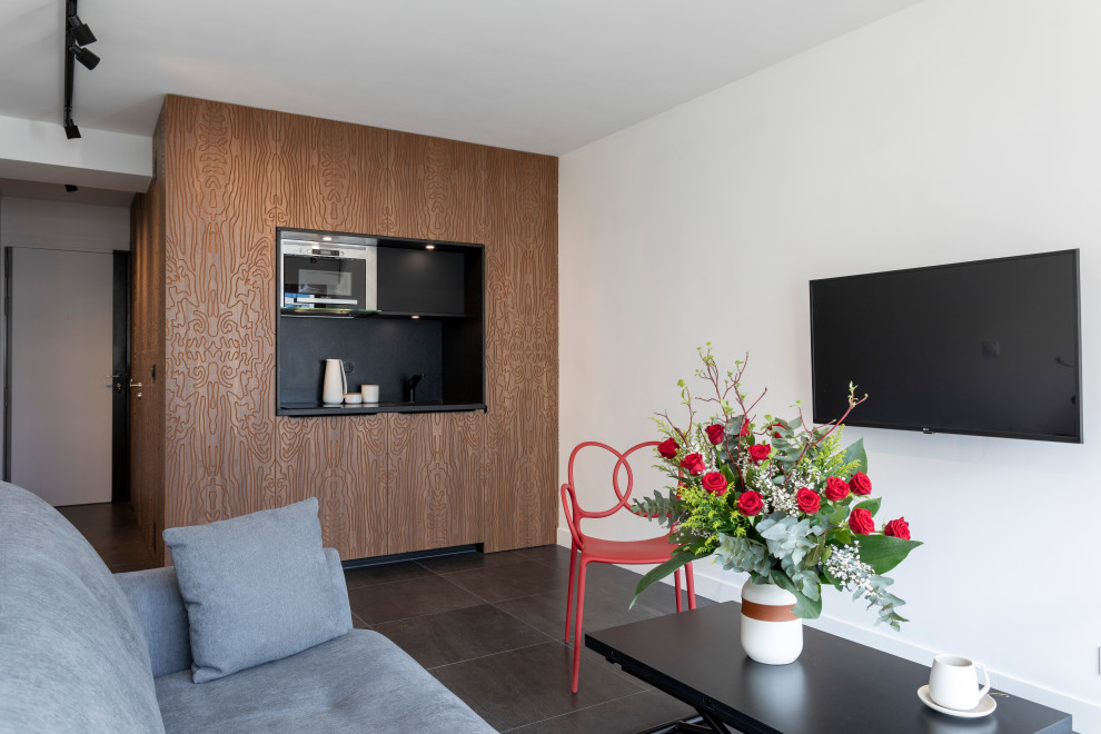 This is an example of a small contemporary open concept living room in Paris with white walls, ceramic floors, no fireplace, a wall-mounted tv and black floor.