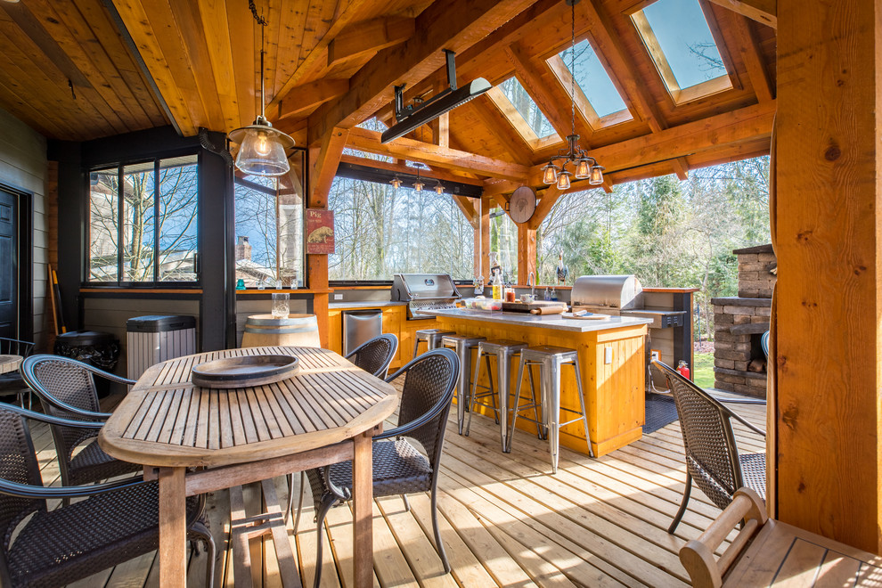 Large mountain style backyard outdoor kitchen deck photo in Vancouver with a roof extension