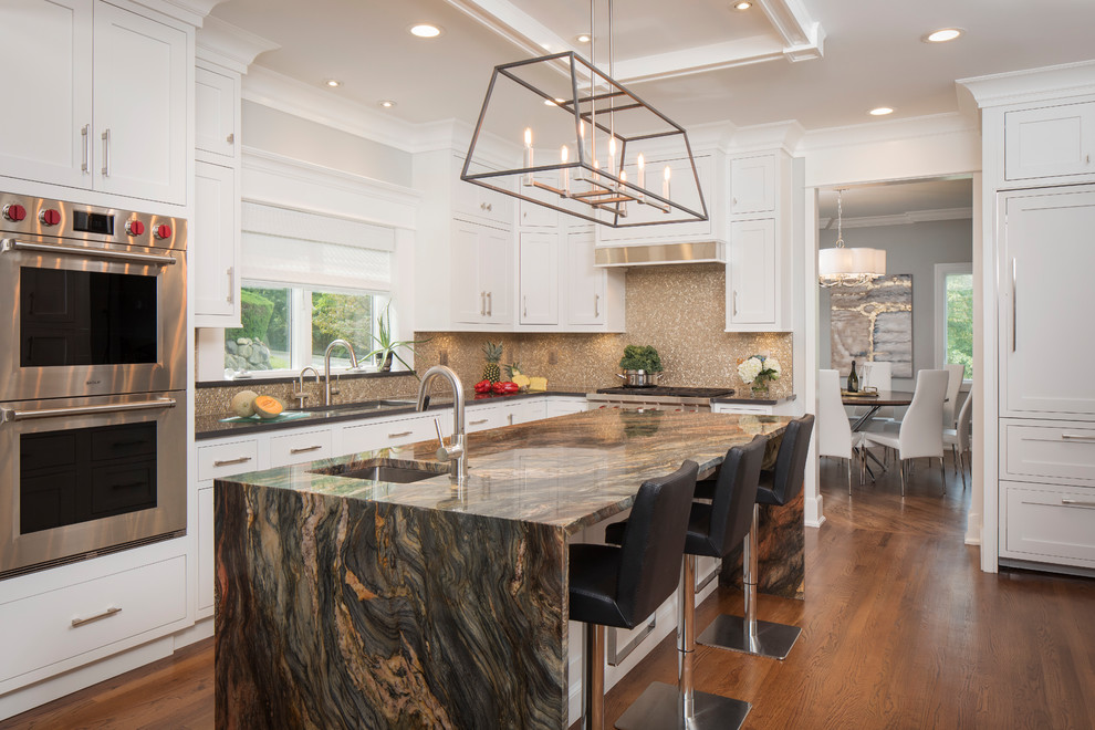 Photo of a large transitional l-shaped kitchen in New York with an undermount sink, shaker cabinets, white cabinets, quartz benchtops, grey splashback, mosaic tile splashback, stainless steel appliances, medium hardwood floors, with island, brown floor and grey benchtop.