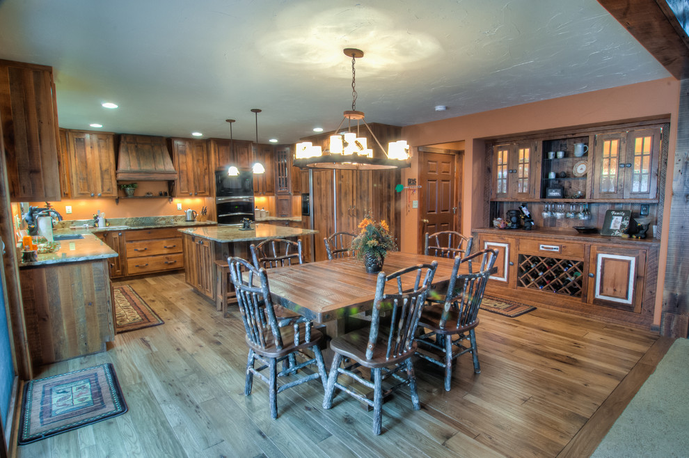 Example of a mountain style u-shaped eat-in kitchen design with an undermount sink, raised-panel cabinets, granite countertops, beige backsplash and stainless steel appliances
