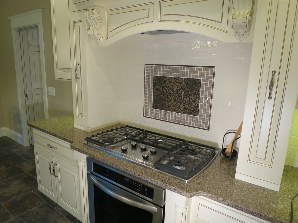 Large transitional galley porcelain tile eat-in kitchen photo with raised-panel cabinets, distressed cabinets, quartz countertops, white backsplash, ceramic backsplash, stainless steel appliances and a peninsula