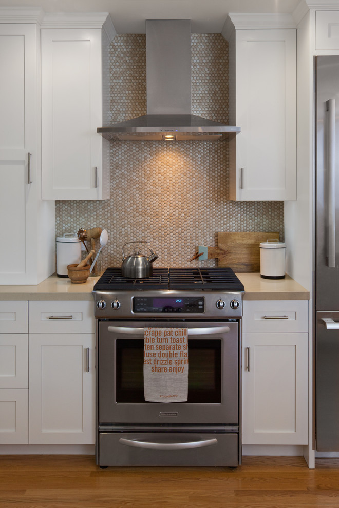 Inspiration for a mid-sized transitional u-shaped separate kitchen in San Francisco with a farmhouse sink, shaker cabinets, white cabinets, quartz benchtops, beige splashback, mosaic tile splashback, stainless steel appliances, medium hardwood floors, a peninsula, brown floor and beige benchtop.