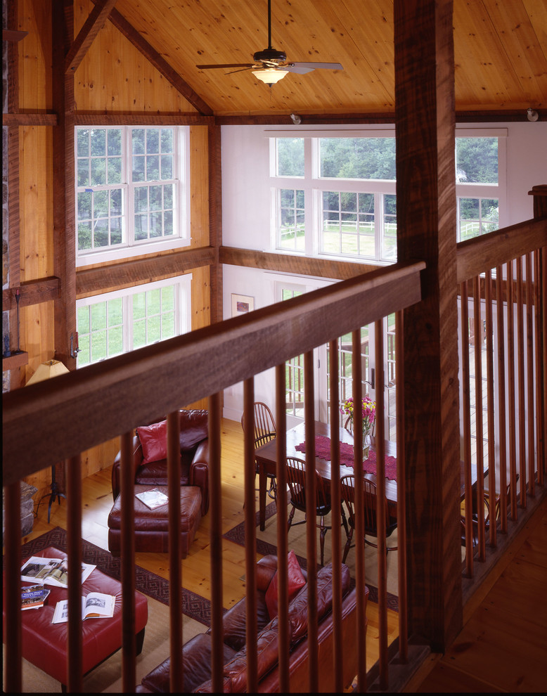 Photo of a large traditional loft-style family room in Manchester with light hardwood floors, a standard fireplace and a stone fireplace surround.