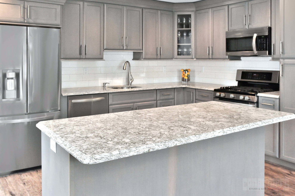 Photo of a large l-shaped eat-in kitchen in New York with an undermount sink, shaker cabinets, grey cabinets, quartz benchtops, white splashback, stainless steel appliances, with island and white benchtop.