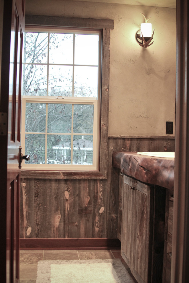Example of a small mountain style 3/4 brown tile slate floor bathroom design with distressed cabinets, wood countertops and beige walls