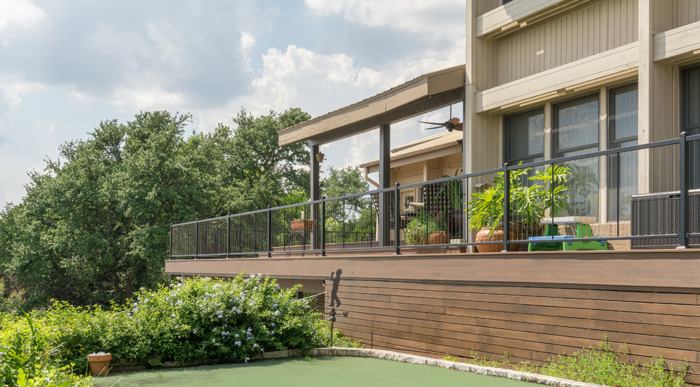 This is an example of an expansive contemporary backyard deck in Austin with a roof extension.