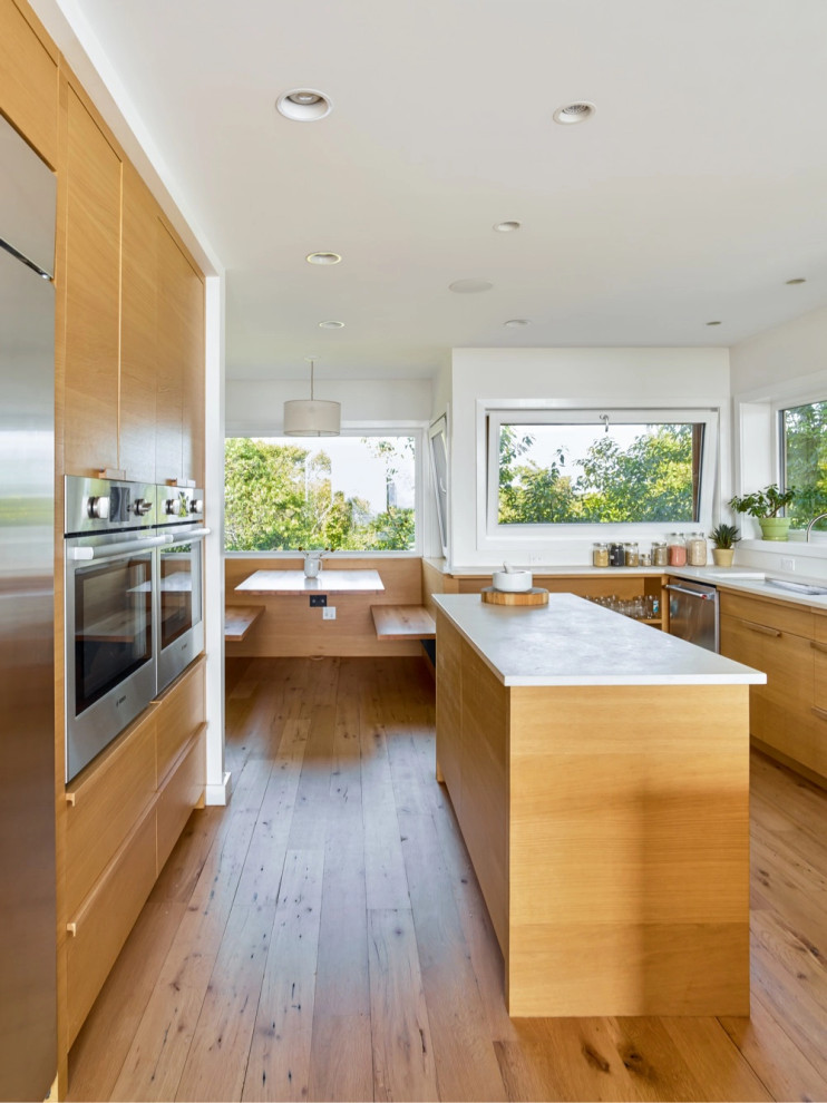 Foto di un cucina con isola centrale stile marino con elettrodomestici in acciaio inossidabile e pavimento in legno massello medio