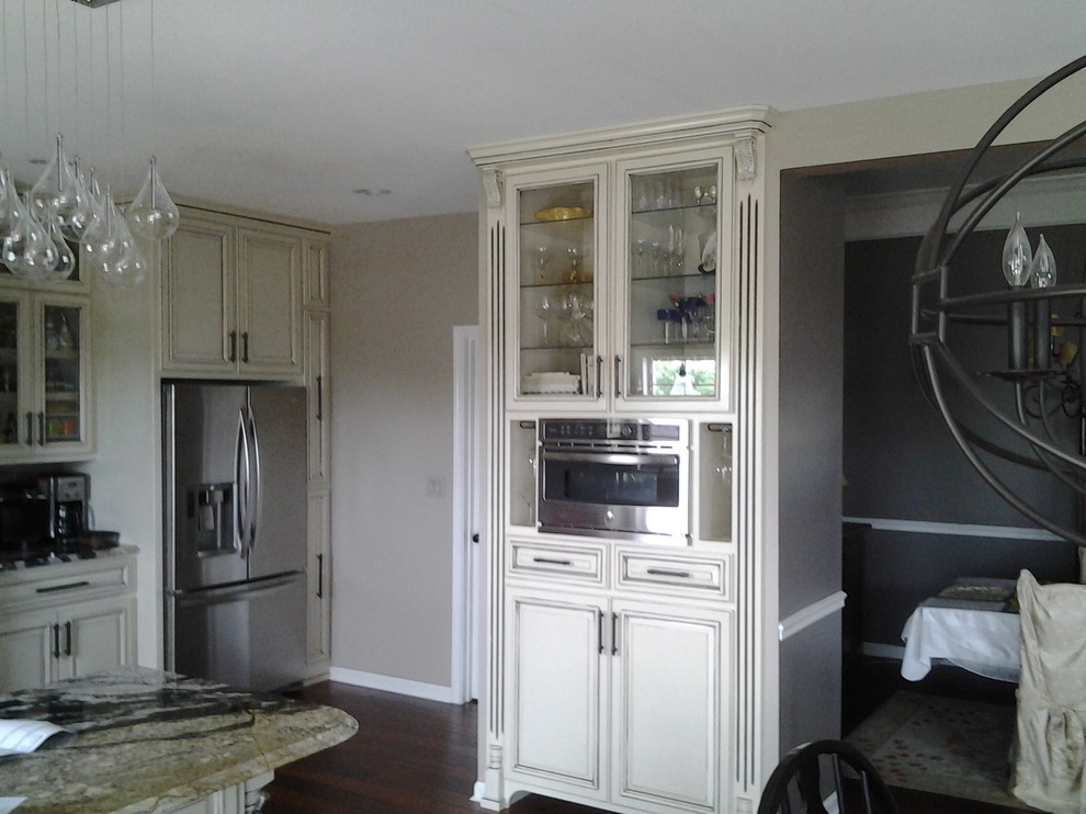 Inspiration for a mid-sized transitional l-shaped dark wood floor and brown floor enclosed kitchen remodel with an undermount sink, raised-panel cabinets, distressed cabinets, granite countertops, gray backsplash, subway tile backsplash, stainless steel appliances and a peninsula