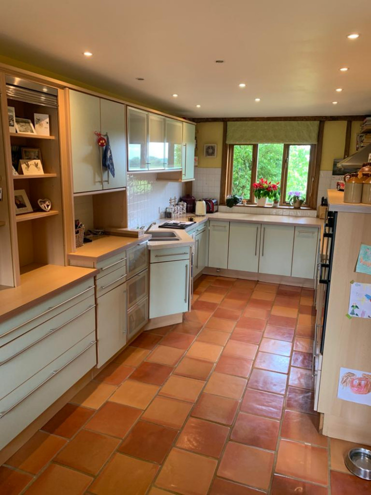 This is an example of a large traditional u-shaped open plan kitchen in Cambridgeshire with a farmhouse sink, beaded inset cabinets, grey cabinets, quartzite benchtops, metallic splashback, mirror splashback, stainless steel appliances, ceramic floors, with island, grey floor and white benchtop.