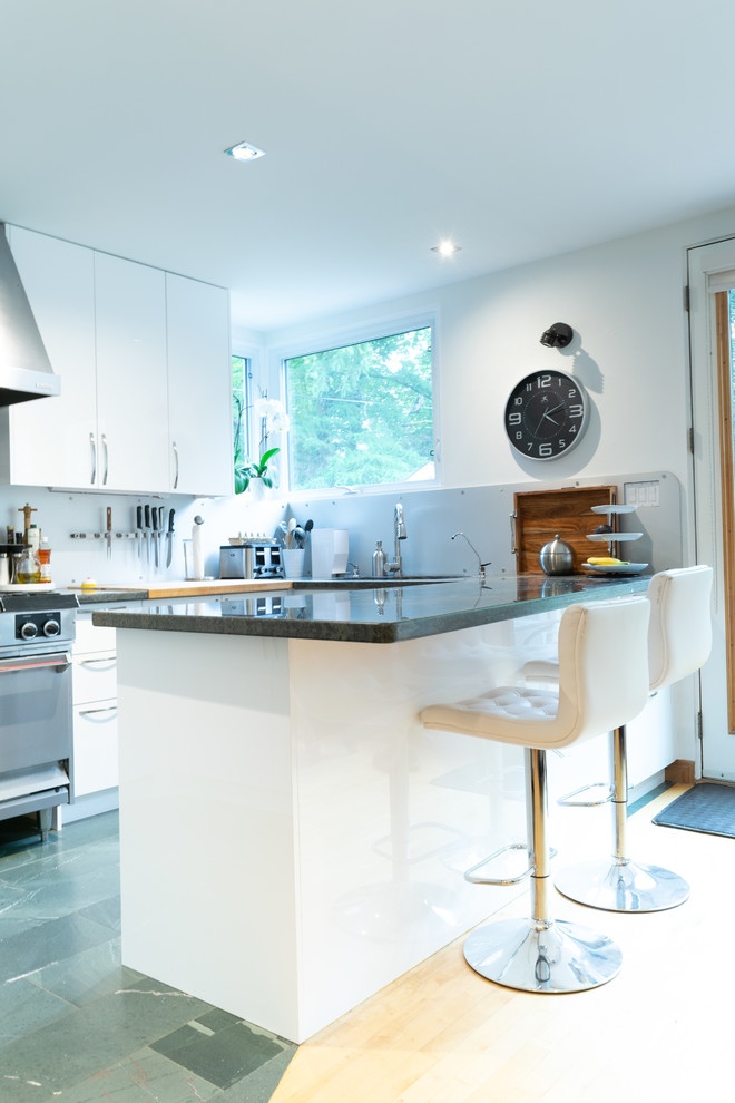 This is an example of a mid-sized modern l-shaped open plan kitchen in Toronto with an undermount sink, flat-panel cabinets, white cabinets, granite benchtops, grey splashback, metal splashback, stainless steel appliances, ceramic floors, a peninsula, green floor and green benchtop.