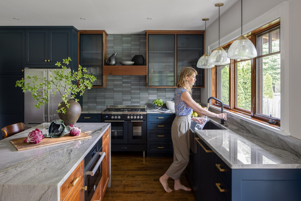 Inspiration for a mid-sized transitional l-shaped open plan kitchen in Louisville with a farmhouse sink, shaker cabinets, blue splashback, ceramic splashback, black appliances, dark hardwood floors, with island, brown floor and grey benchtop.