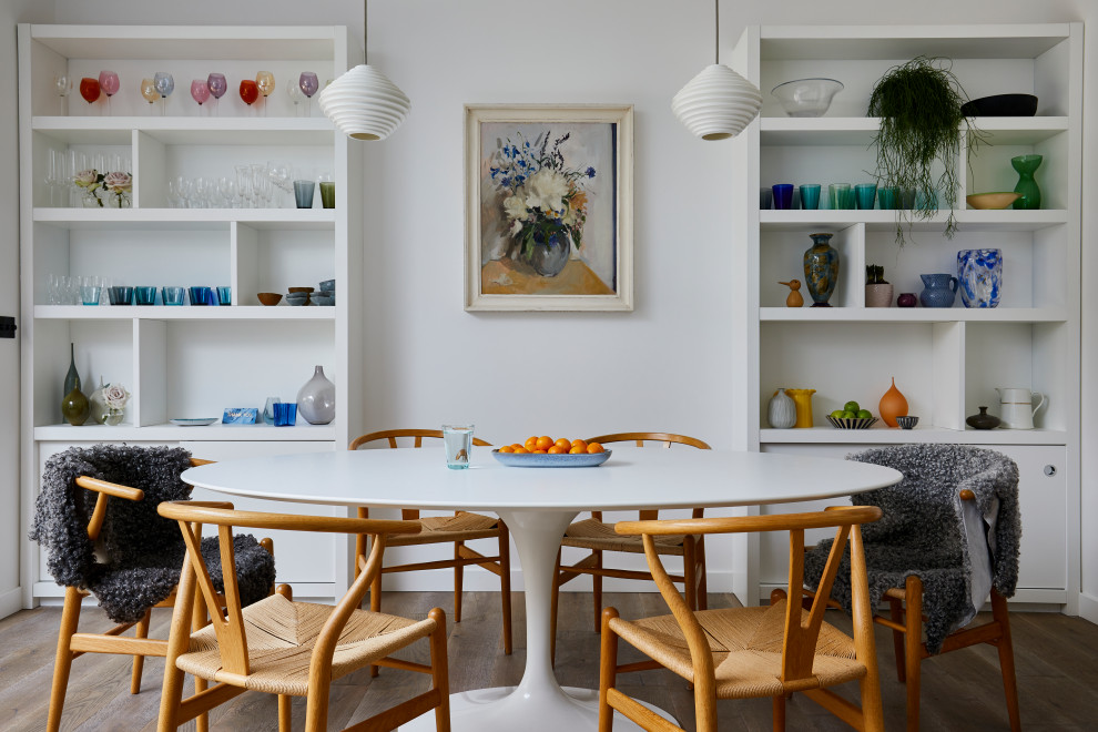 Immagine di una sala da pranzo aperta verso la cucina contemporanea con pareti bianche, pavimento in legno massello medio, nessun camino e pavimento marrone