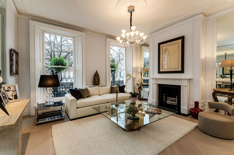Design ideas for a traditional formal enclosed living room in London with white walls, light hardwood floors, a standard fireplace, a stone fireplace surround and no tv.