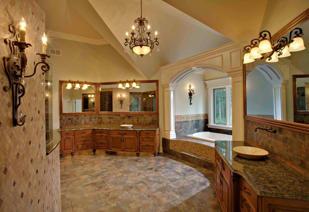 Design ideas for an expansive traditional master wet room bathroom in Chicago with raised-panel cabinets, medium wood cabinets, brown tile, gray tile, stone tile, granite benchtops, a drop-in tub, beige walls, slate floors, a vessel sink, grey floor and an open shower.