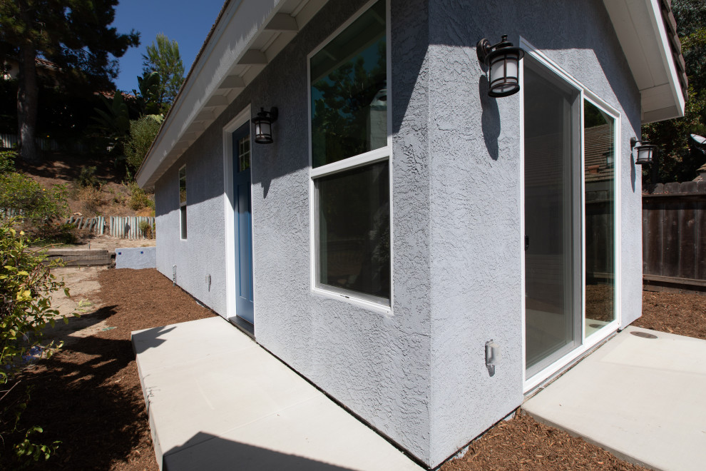 Small beach style one-storey stucco grey exterior in San Diego with a gable roof and a tile roof.