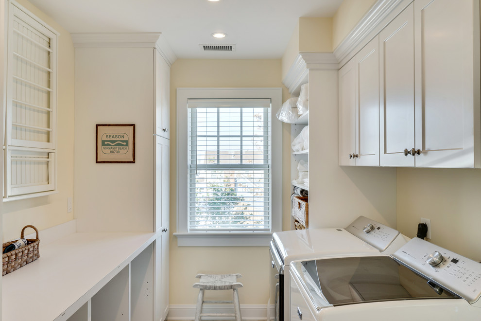 This is an example of a beach style galley laundry room in New York with recessed-panel cabinets, white cabinets, laminate benchtops and beige walls.