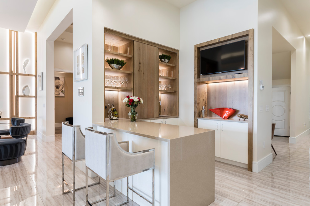 Photo of a contemporary u-shaped home bar in Orlando with flat-panel cabinets, white cabinets, beige floor and beige benchtop.