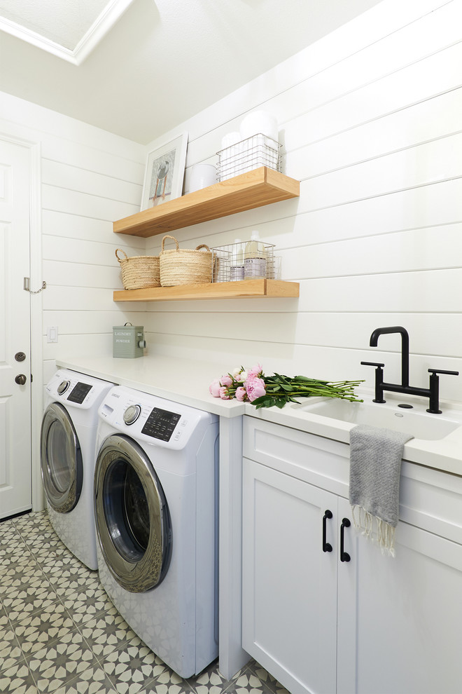 Beach style single-wall dedicated laundry room in San Diego with an undermount sink, shaker cabinets, white cabinets, white walls, a side-by-side washer and dryer, multi-coloured floor and white benchtop.