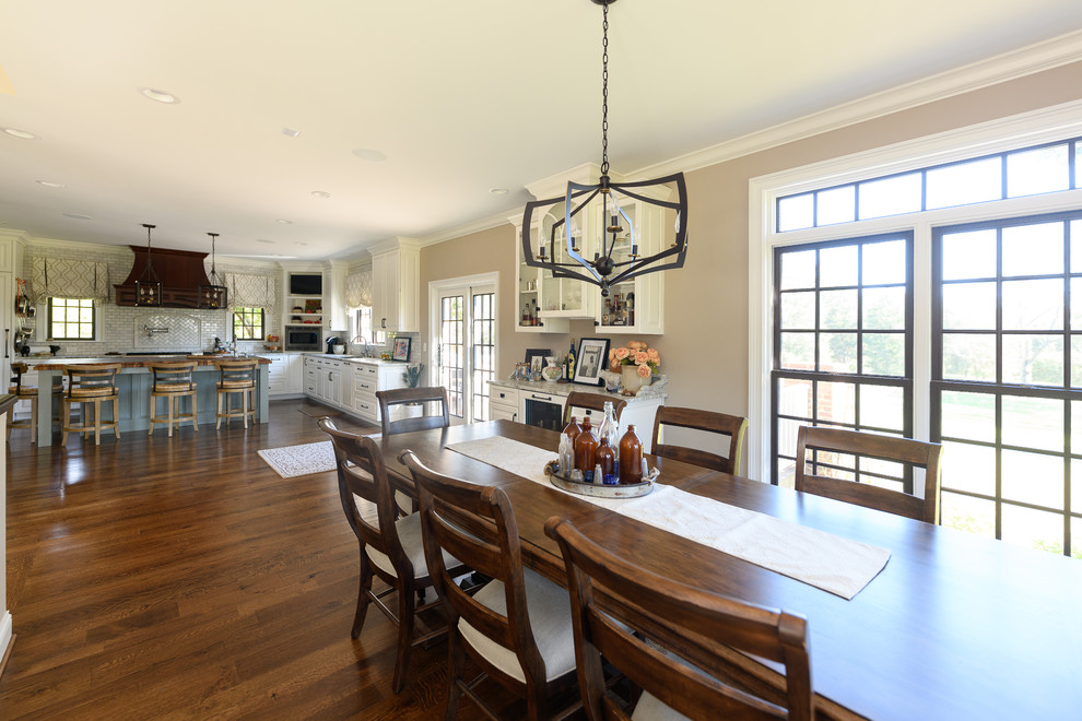 Example of a large transitional l-shaped dark wood floor and brown floor kitchen design with an undermount sink, raised-panel cabinets, white cabinets, quartzite countertops, white backsplash, marble backsplash, stainless steel appliances and an island