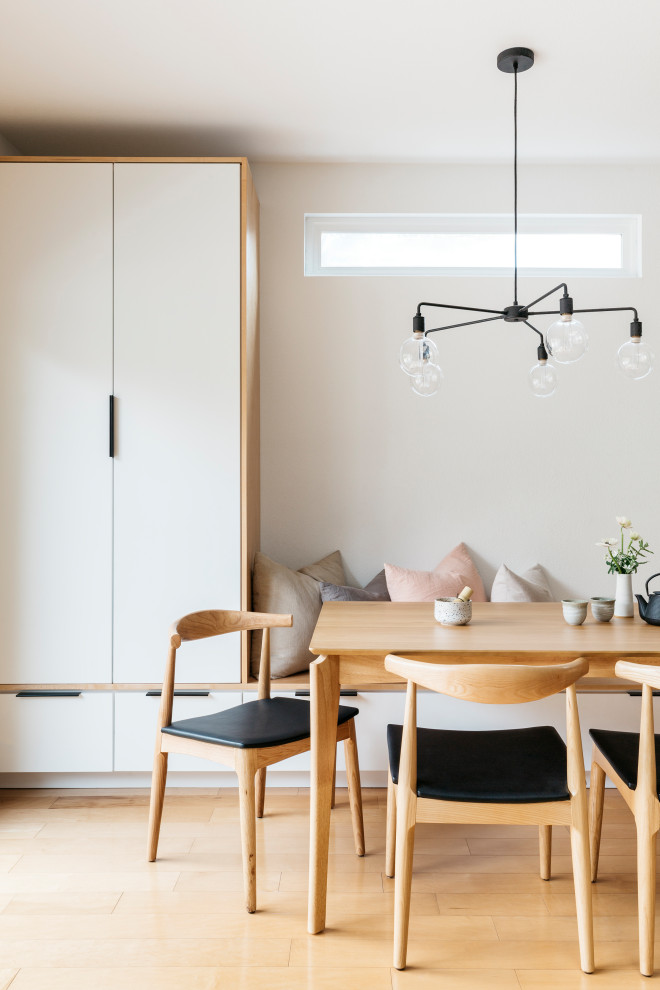 Diseño de comedor escandinavo pequeño abierto sin chimenea con paredes blancas, suelo de madera clara y suelo marrón