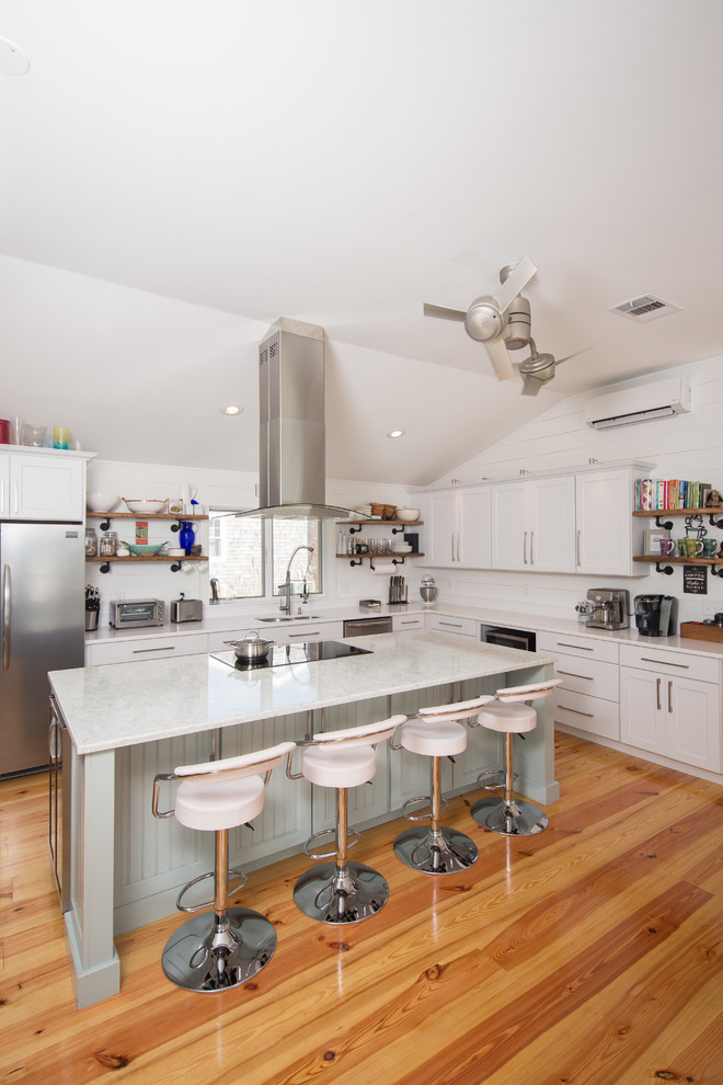 Design ideas for a mid-sized beach style l-shaped eat-in kitchen in Providence with an undermount sink, shaker cabinets, white cabinets, quartz benchtops, white splashback, timber splashback, stainless steel appliances, light hardwood floors, with island and yellow floor.