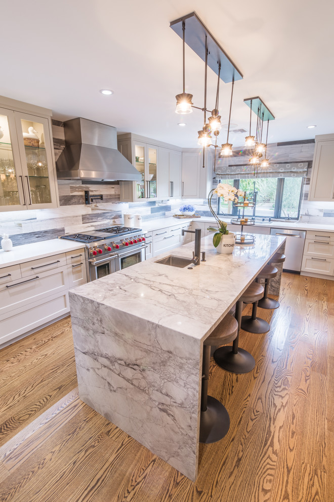 Inspiration for a large modern l-shaped open plan kitchen in Los Angeles with an undermount sink, shaker cabinets, beige cabinets, quartzite benchtops, grey splashback, porcelain splashback, stainless steel appliances, medium hardwood floors and with island.