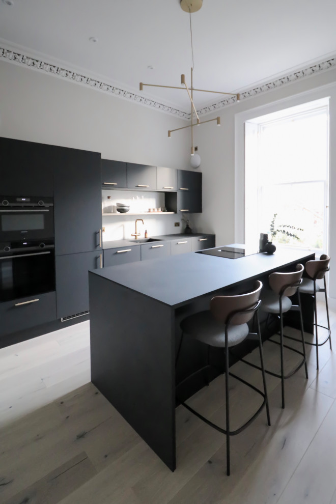 Inspiration för ett avskilt, mellanstort skandinaviskt svart linjärt svart kök, med en undermonterad diskho, släta luckor, svarta skåp, bänkskiva i koppar, vitt stänkskydd, stänkskydd i keramik, svarta vitvaror, ljust trägolv, en köksö och beiget golv