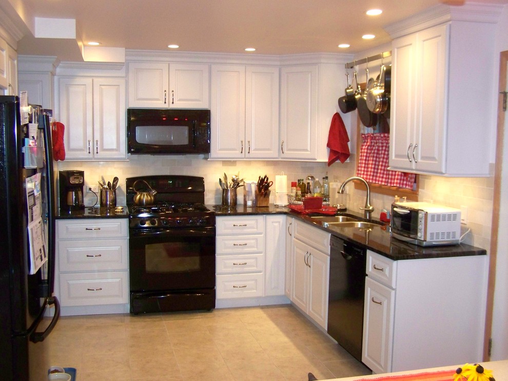 Photo of a traditional u-shaped eat-in kitchen in Chicago with an undermount sink, raised-panel cabinets, white cabinets, granite benchtops, beige splashback, subway tile splashback and black appliances.