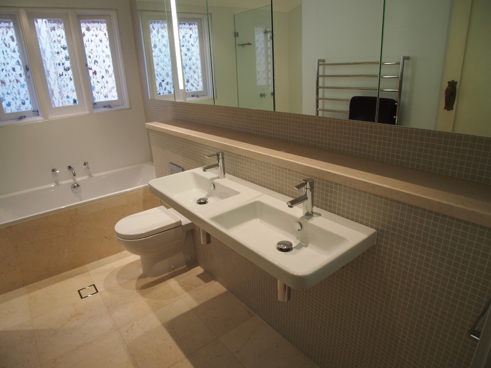 Contemporary bathroom in Other with limestone benchtops, a wall-mount sink, beige tile, beige walls, limestone floors and a curbless shower.