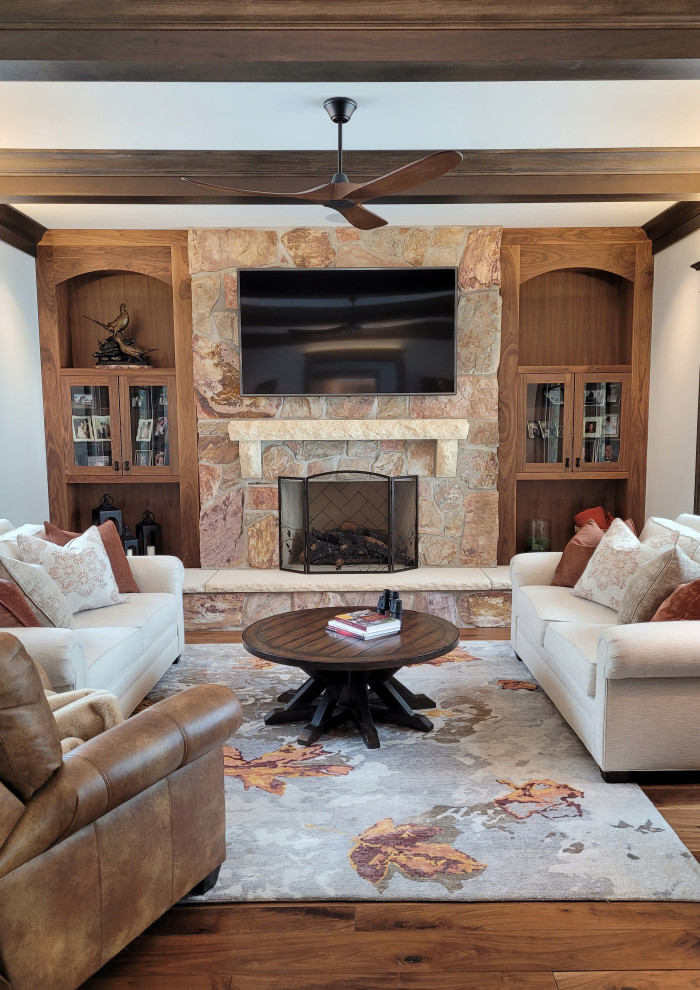 Example of a mid-sized transitional enclosed medium tone wood floor, brown floor and exposed beam living room library design in Milwaukee with beige walls, a standard fireplace and a stone fireplace