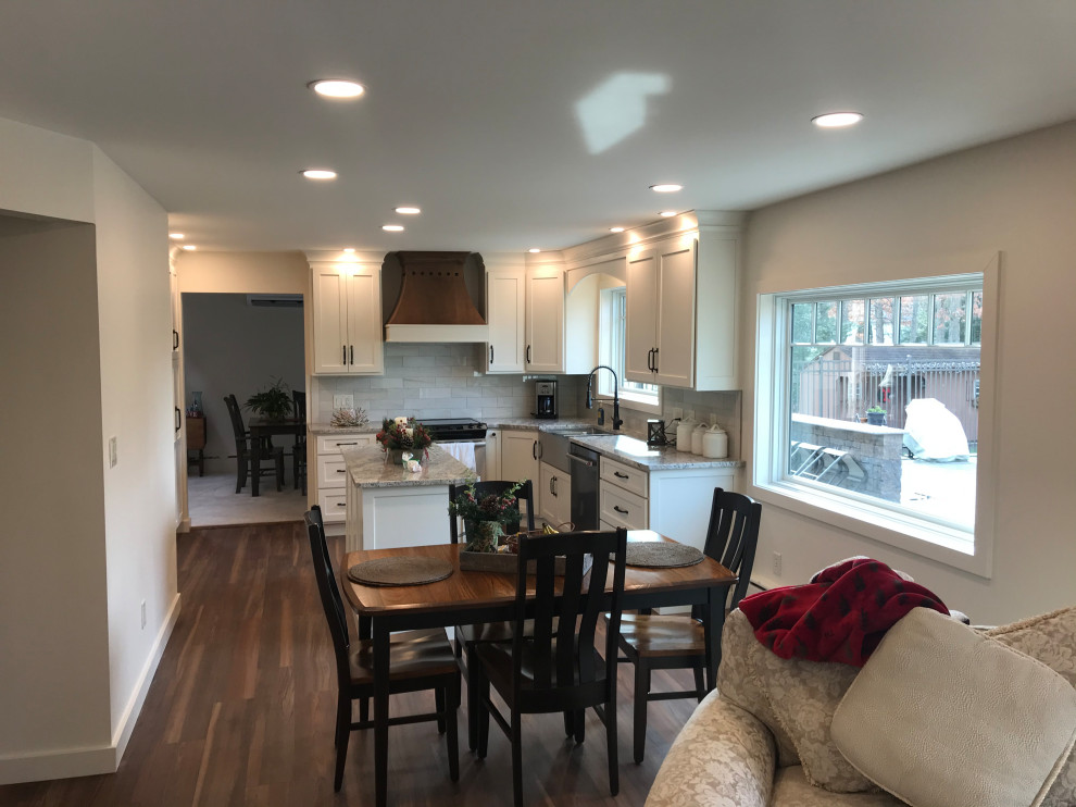 Example of a mid-sized minimalist u-shaped vinyl floor and brown floor eat-in kitchen design with a farmhouse sink, recessed-panel cabinets, white cabinets, granite countertops, gray backsplash, porcelain backsplash, stainless steel appliances, an island and gray countertops