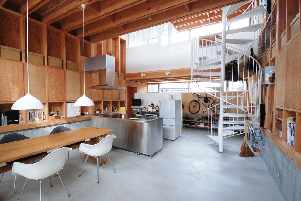 This is an example of an industrial open plan dining in Tokyo Suburbs with beige walls and concrete floors.