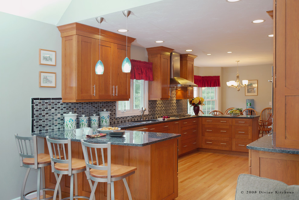 This is an example of a large eclectic galley eat-in kitchen in Boston with a double-bowl sink, shaker cabinets, medium wood cabinets, granite benchtops, blue splashback, mosaic tile splashback, stainless steel appliances, light hardwood floors and no island.