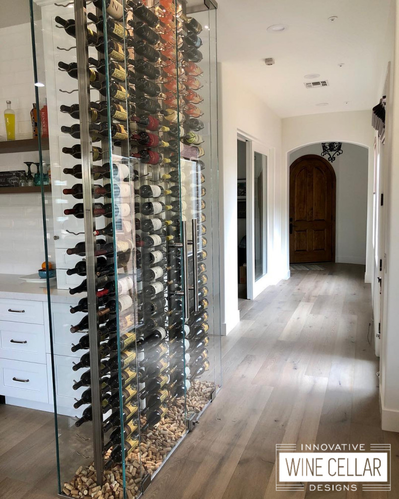 Design ideas for a small contemporary wine cellar in Other with light hardwood flooring, display racks and brown floors.