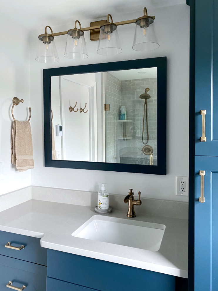 Klassisches Badezimmer mit profilierten Schrankfronten, blauen Schränken, Duschnische, Wandtoilette mit Spülkasten, weißer Wandfarbe, Porzellan-Bodenfliesen, Unterbauwaschbecken, Quarzwerkstein-Waschtisch, blauem Boden, Falttür-Duschabtrennung, weißer Waschtischplatte, Einzelwaschbecken und eingebautem Waschtisch in Boston