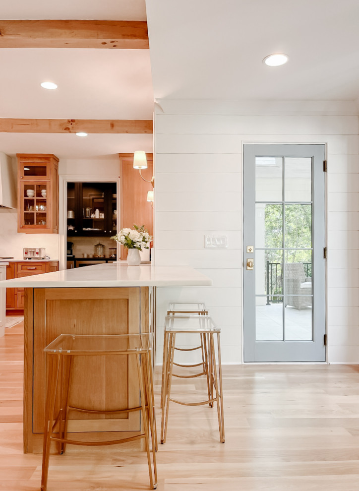 Town + Country Addition and Renovation - Our clients wanted a kitchen that could keep up with their family's pace. They love watching cooking competitions and wanted their kitchen to be the perfect spot for their kids to have cookie bake-offs. To make that possible, their kitchen needed to be wider, more capable, and more open than their current one, while still feeling connected to the family room. The wife wanted to be present with her family even while cooking, with a clear view of both the breakfast room and the family room wherever she stood. That sightline became the guiding principle for the entire space.

What came together is nothing short of a dream kitchen. The footprint was dramatically expanded as part of the addition, anchored by an oversized island with a bright quartz countertop that invites the whole family to pull up a stool and stay a while. Warm, natural wood cabinetry wraps the perimeter, grounding the space with richness and texture, while the white island keeps everything feeling bright and open. Exposed wood beams overhead carry warmth upward, and a pair of brass lantern pendants over the island add just the right amount of drama without competing with the natural light pouring in through the wall of windows in the breakfast room.

The butler's pantry, tucked just off the kitchen, adds the kind of storage and prep space that makes a busy household run smoothly, and gives the whole cooking experience a sense of ease and luxury that the family now wonders how they ever lived without. And with the family room and breakfast room always in view, separated only by open air, this kitchen doesn't just function beautifully. It draws everyone together exactly the way our clients always hoped it would.