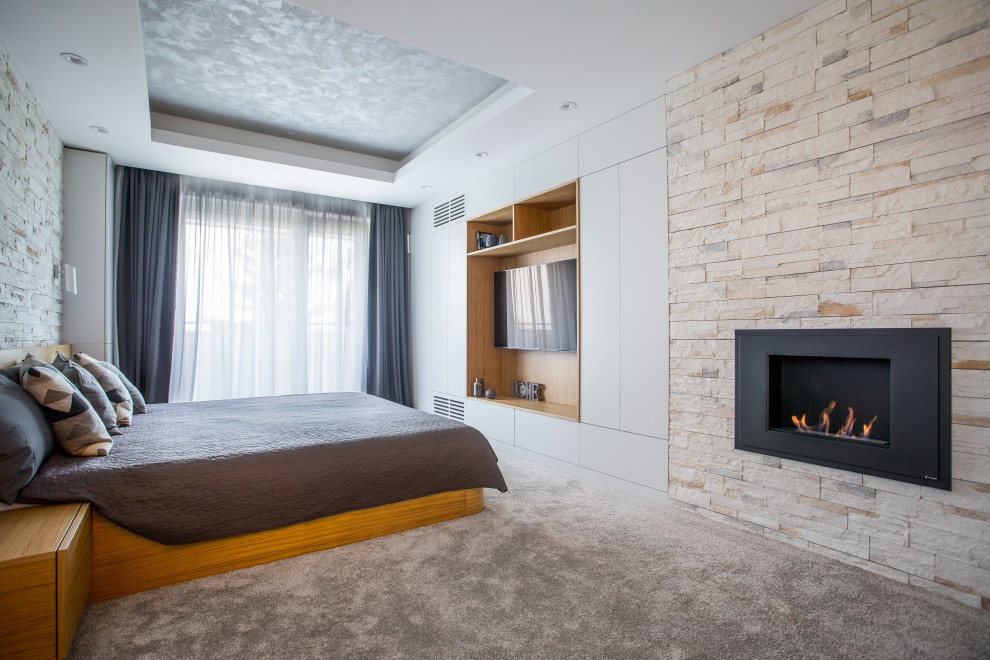 Design ideas for a large contemporary master bedroom in Other with grey walls, carpet, a standard fireplace, a stone fireplace surround, grey floors, a drop ceiling and brick walls.