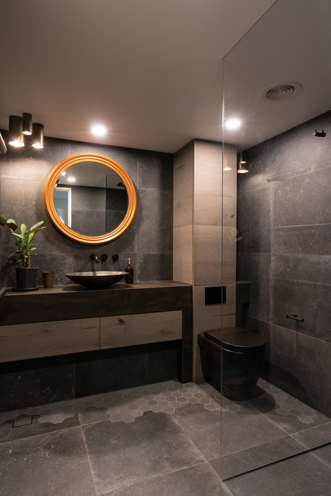 This is an example of a small contemporary master bathroom in Sydney with engineered quartz benchtops, furniture-like cabinets, light wood cabinets, an open shower, a one-piece toilet, gray tile, porcelain tile, grey walls, porcelain floors, a vessel sink, grey floor and brown benchtops.