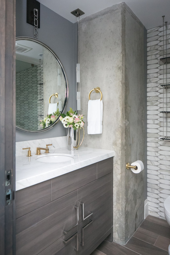 Design ideas for a mid-sized industrial 3/4 wet room bathroom in Denver with flat-panel cabinets, grey cabinets, a two-piece toilet, gray tile, marble, grey walls, porcelain floors, an undermount sink, quartzite benchtops, grey floor and a hinged shower door.