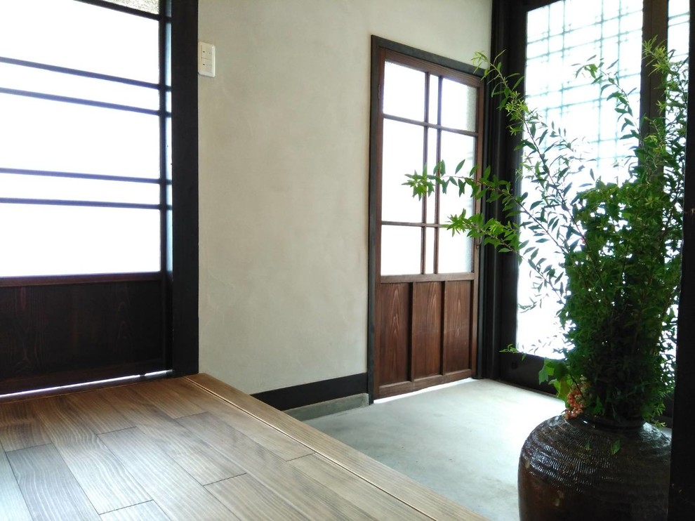 Small asian entry hall in Other with grey walls, medium hardwood floors, a sliding front door, a brown front door and brown floor.