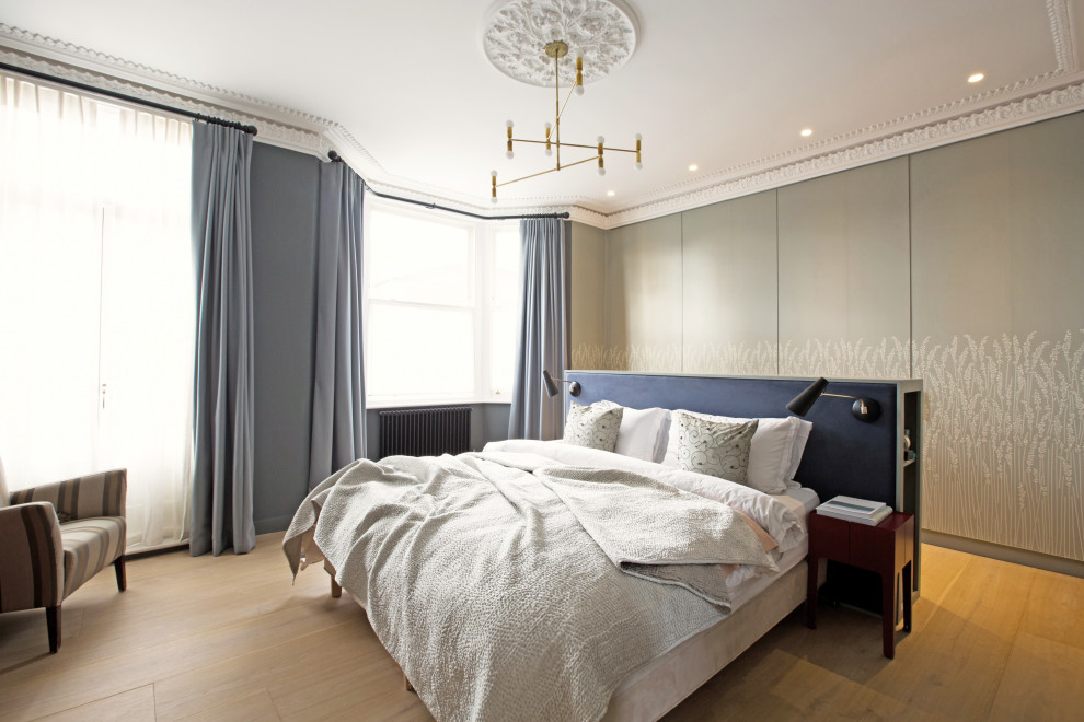 Geräumiges Nordisches Hauptschlafzimmer ohne Kamin mit grüner Wandfarbe und hellem Holzboden in London