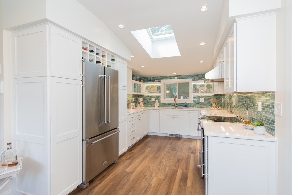 Inspiration for a small beach style u-shaped separate kitchen in Boston with an undermount sink, shaker cabinets, white cabinets, quartz benchtops, green splashback, subway tile splashback, stainless steel appliances, medium hardwood floors, no island and white benchtop.