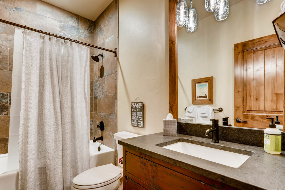 Photo of a small country kids bathroom in Denver with shaker cabinets, red cabinets, a two-piece toilet, brown tile, ceramic tile, beige walls, ceramic floors, an undermount sink, granite benchtops, brown floor and a hinged shower door.
