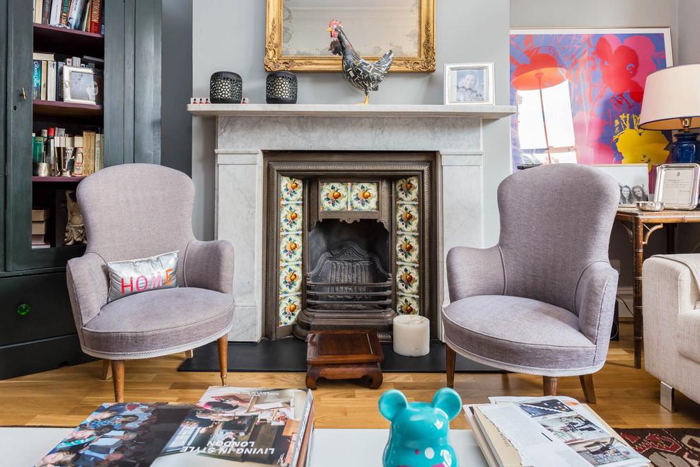 Photo of an eclectic living room in London with grey walls, medium hardwood floors, a standard fireplace, a tile fireplace surround and brown floor.