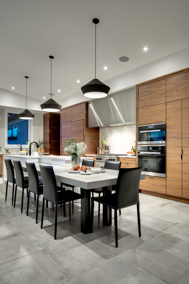 This is an example of a large contemporary l-shaped eat-in kitchen in Calgary with an undermount sink, flat-panel cabinets, medium wood cabinets, quartz benchtops, white splashback, marble splashback, panelled appliances, ceramic floors, with island, grey floor and white benchtop.
